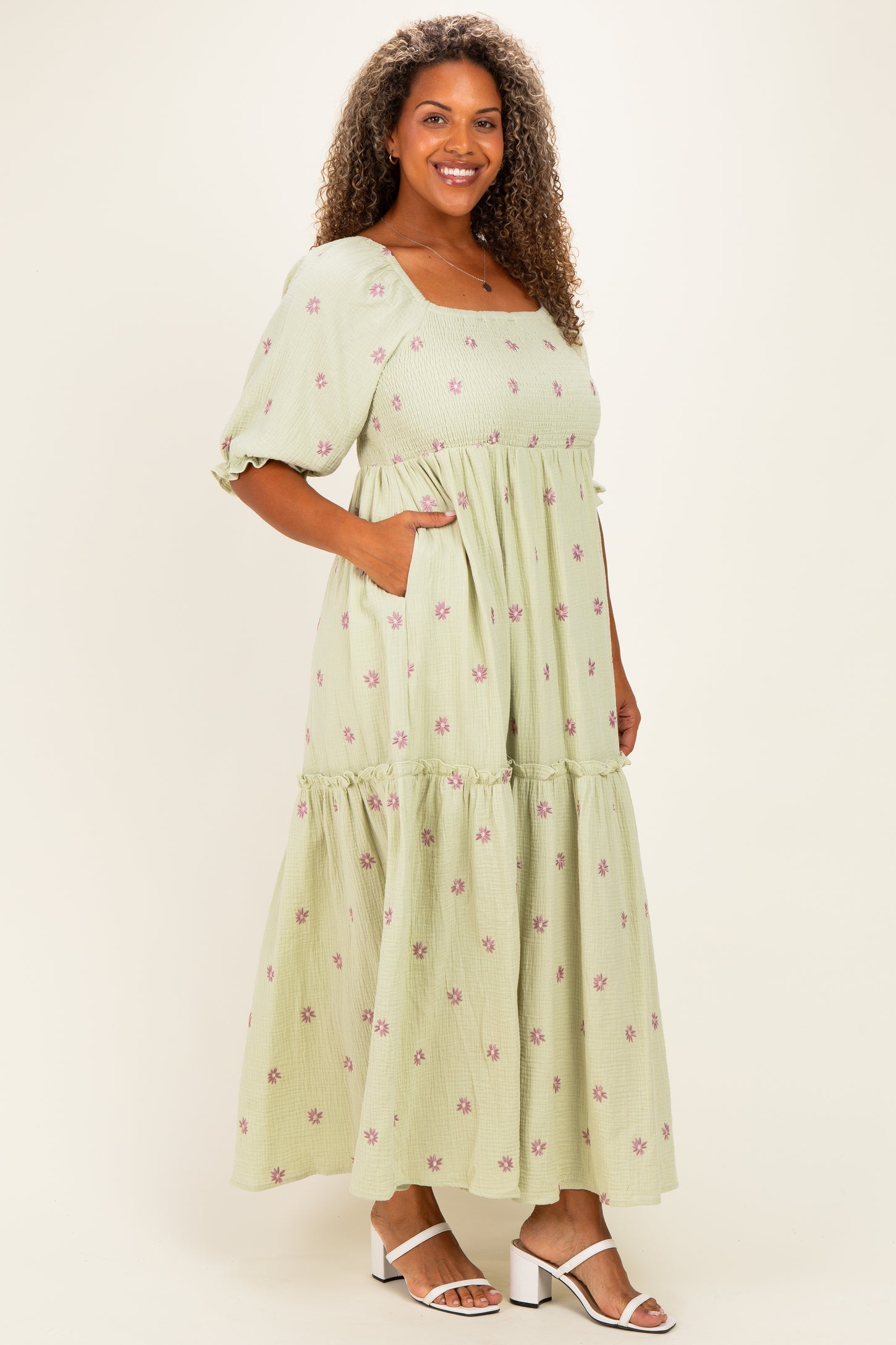 woman wearing a light green floral print maxi dress with puff sleeves and pockets