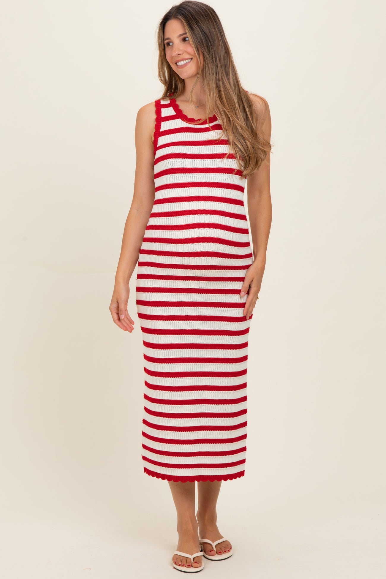 woman wearing a red and white striped maternity dress with a fitted silhouette and scalloped hem, showing her baby bump