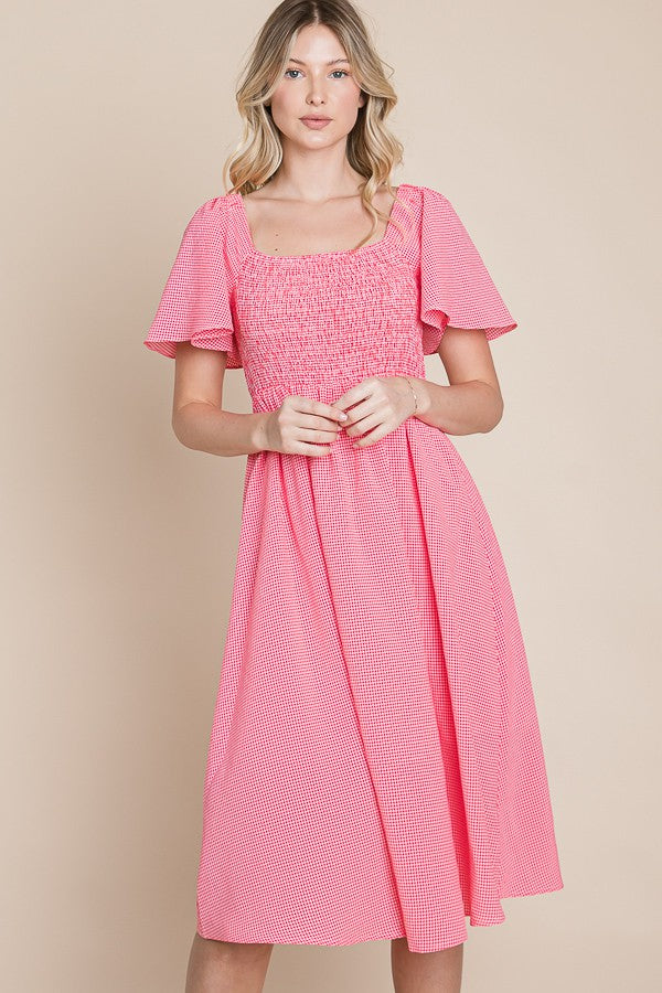 woman wearing a pink smocked midi dress with short sleeves and a square neckline