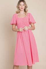 woman wearing a pink smocked midi dress with short sleeves and a square neckline