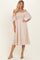 woman wearing a light beige off-the-shoulder midi dress with a smocked bodice and flowy sleeves.