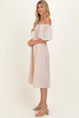 woman wearing a blush off-the-shoulder midi dress with puff sleeves and a smocked bodice