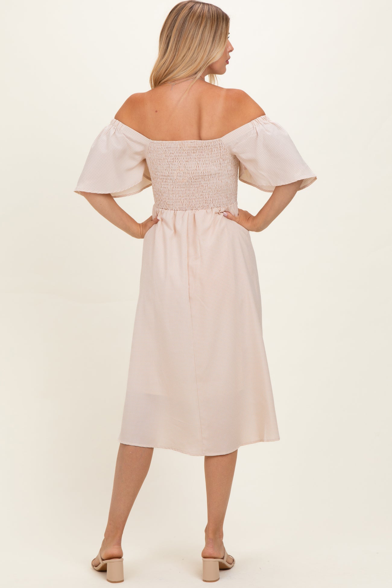 woman wearing a blush off-the-shoulder midi dress with a smocked bodice and puff sleeves, shown from the back