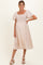 woman wearing a light pink maternity dress with a smocked bodice and puff sleeves, showing a baby bump