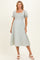 woman wearing a light green maternity dress with a square neckline and short flutter sleeves