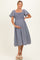 woman wearing a navy and white striped maternity dress with short flutter sleeves and a smocked bodice, holding her baby bump
