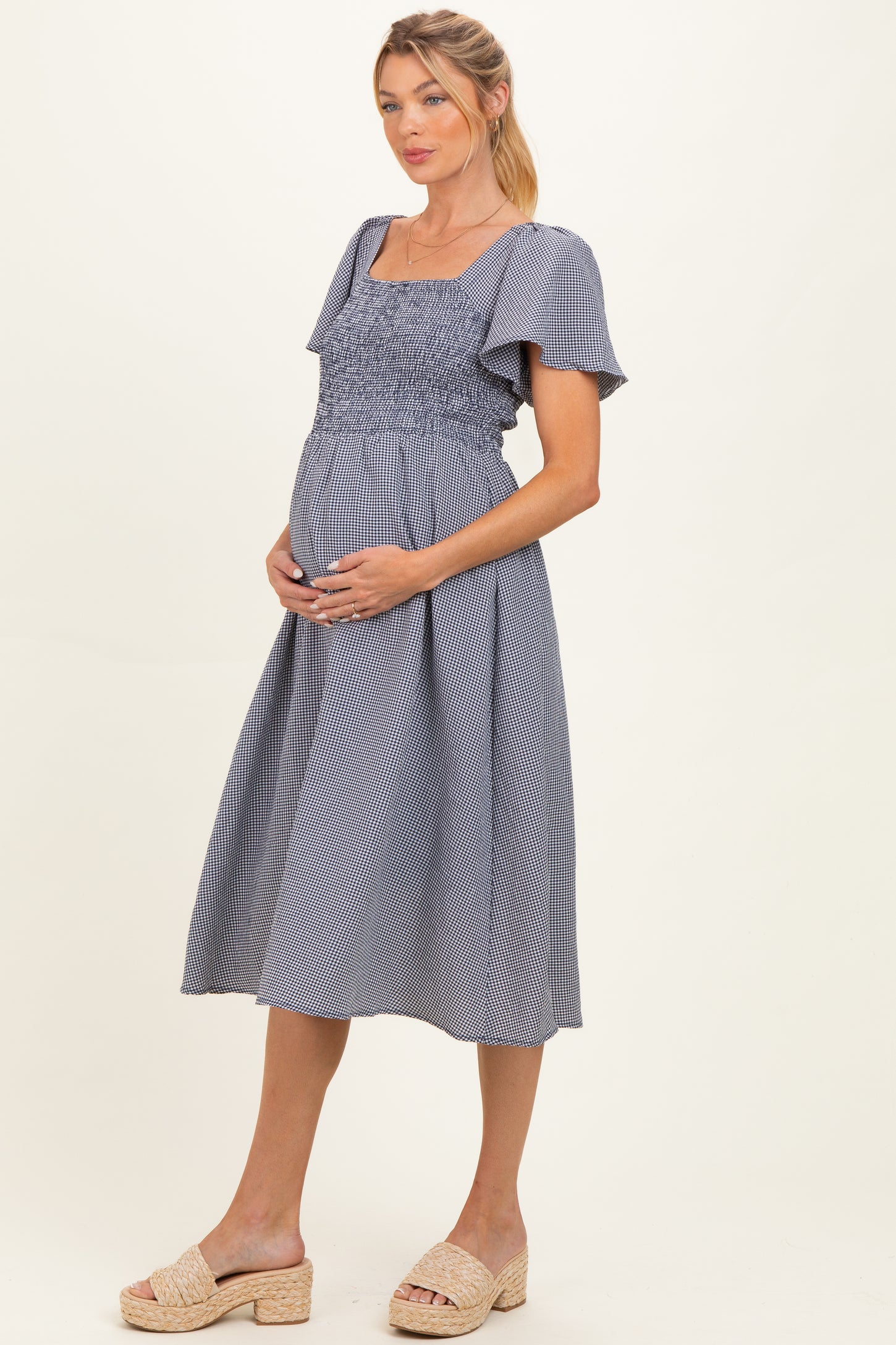 woman wearing a navy and white striped maternity dress with a smocked bodice and short sleeves, showing her baby bump