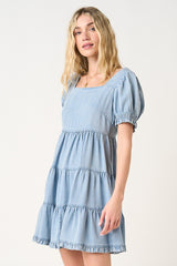 woman wearing a light blue short puff sleeve tiered denim dress with a square neckline