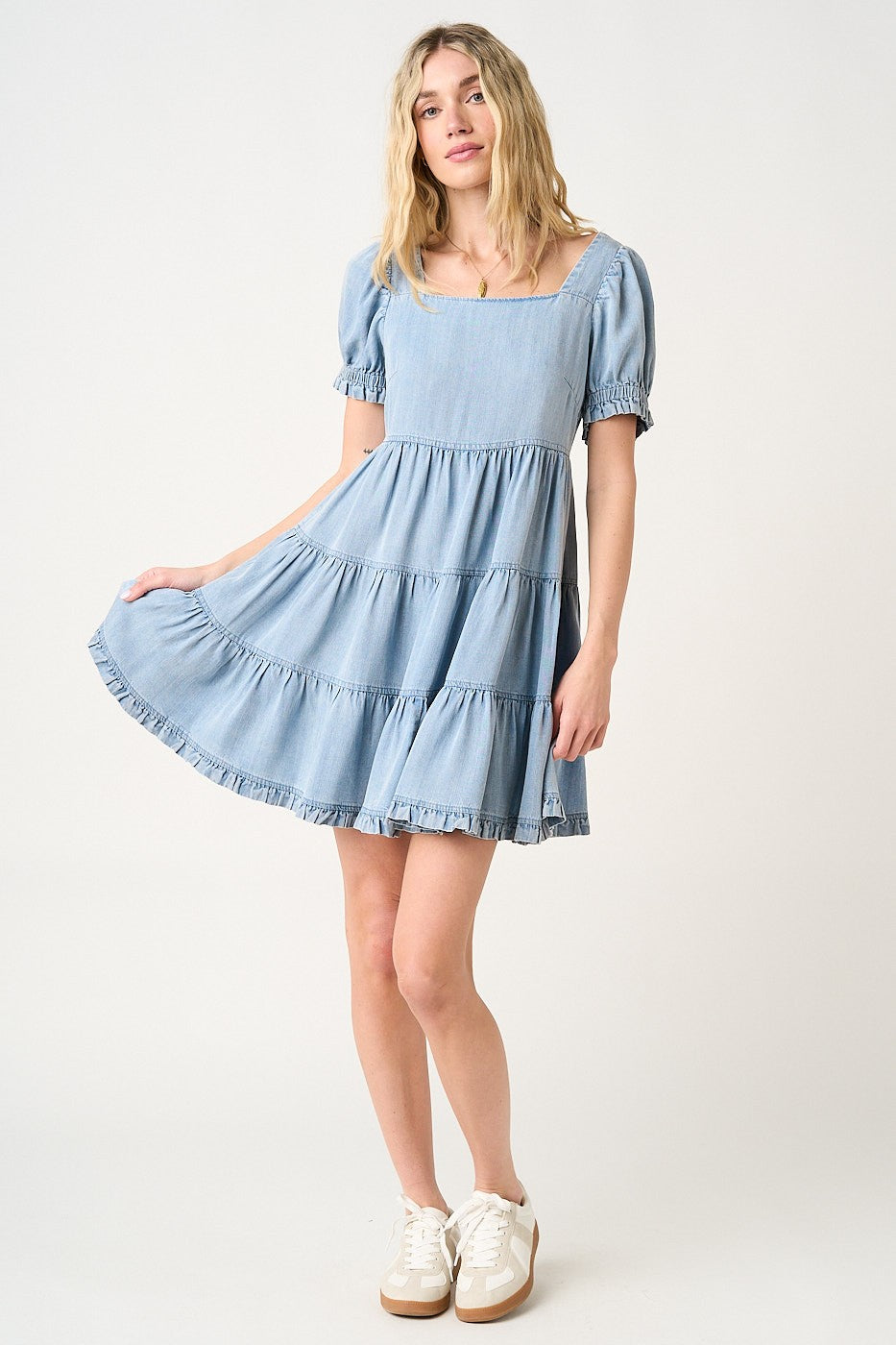 woman wearing a light blue chambray tiered dress with puff sleeves and a square neckline