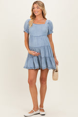 woman wearing a light blue short sleeve maternity dress with a square neckline and ruffled tiers, holding her baby bump