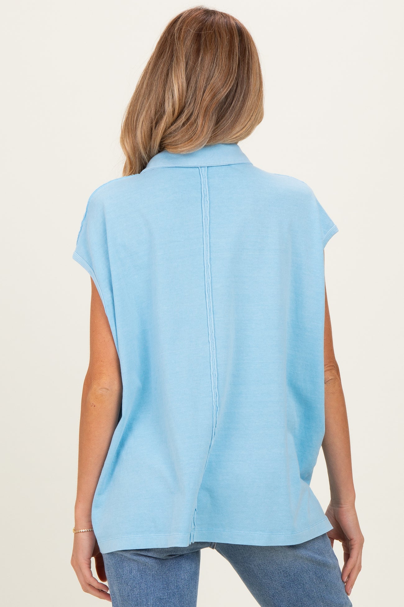 woman wearing a light blue short sleeve maternity top featuring a relaxed fit and back seam detail