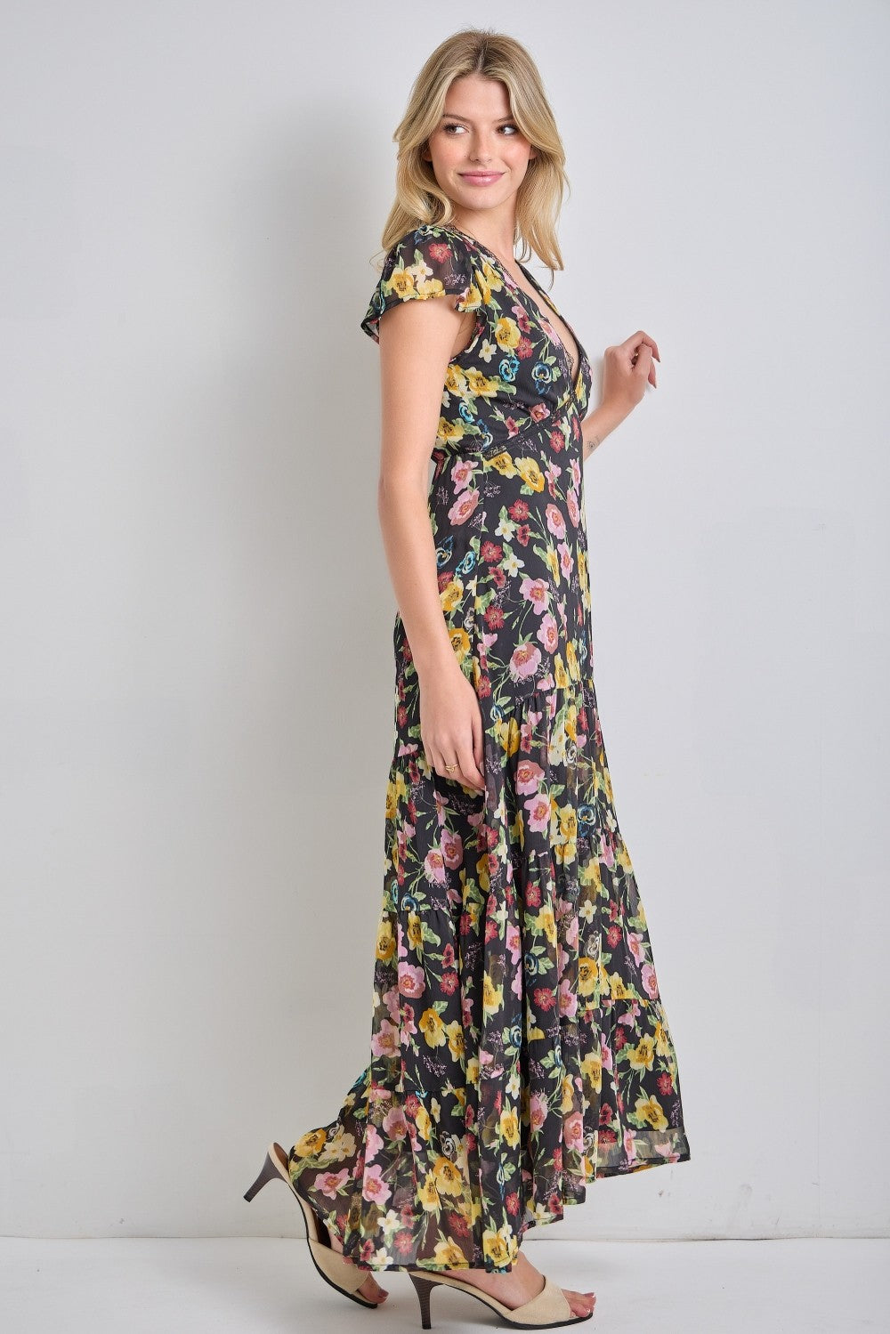 woman wearing a black floral maxi dress with cap sleeves and a flowing hemline