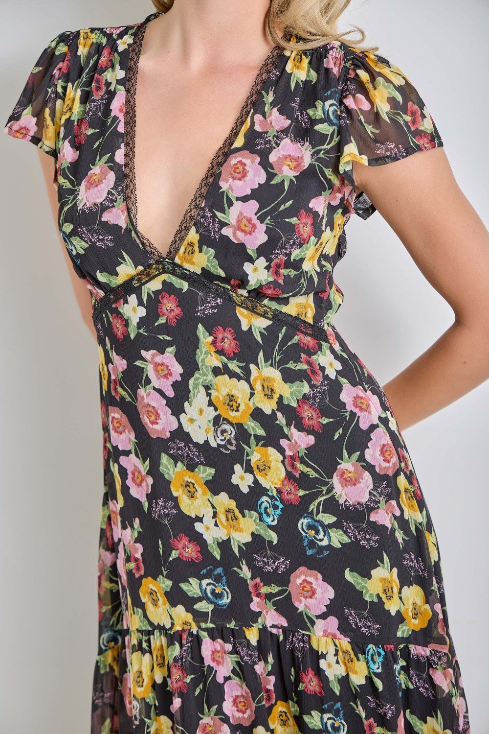 woman wearing a black floral wrap dress with cap sleeves and a deep v-neckline