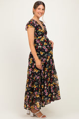 woman wearing a black floral maternity maxi dress with a V-neckline and short flutter sleeves, showcasing her baby bump
