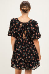 woman wearing a black floral maternity dress with puff sleeves and an open back detail