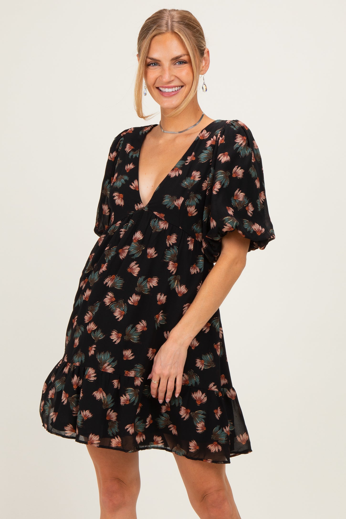 woman wearing a black floral print mini dress with puff sleeves and a deep V-neckline