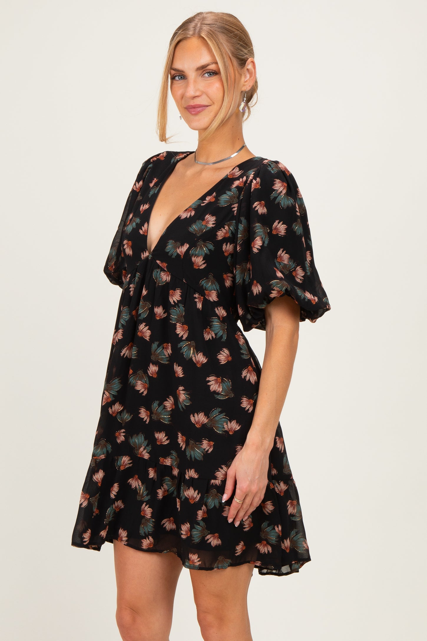 woman wearing a black floral puff sleeve mini dress with a deep V-neckline and a flared skirt