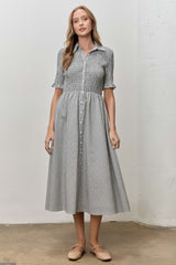 woman wearing a gray and white checked button-up dress with short sleeves and a gathered waist