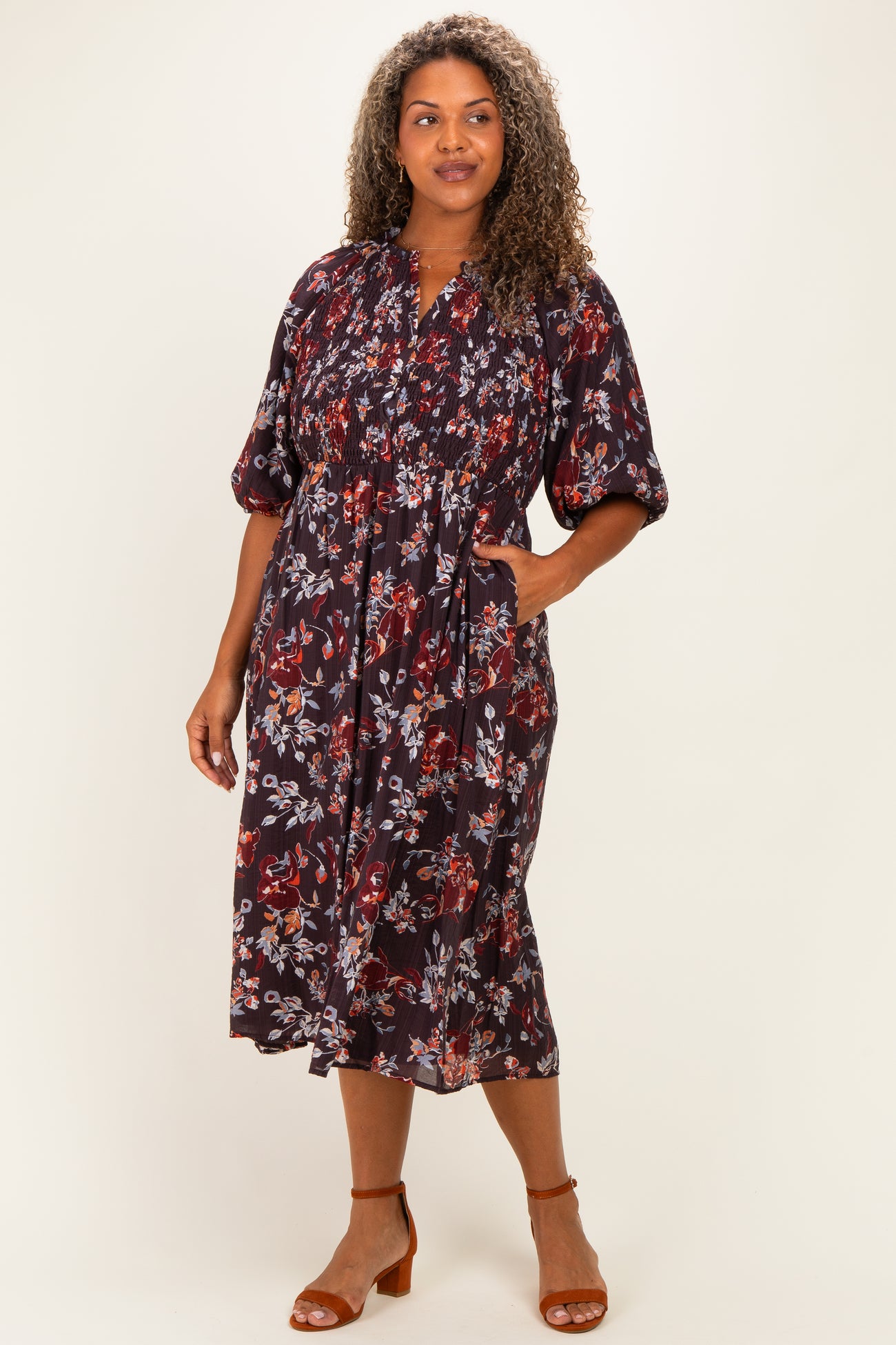 woman wearing a dark floral midi dress with a gathered neckline and short puff sleeves