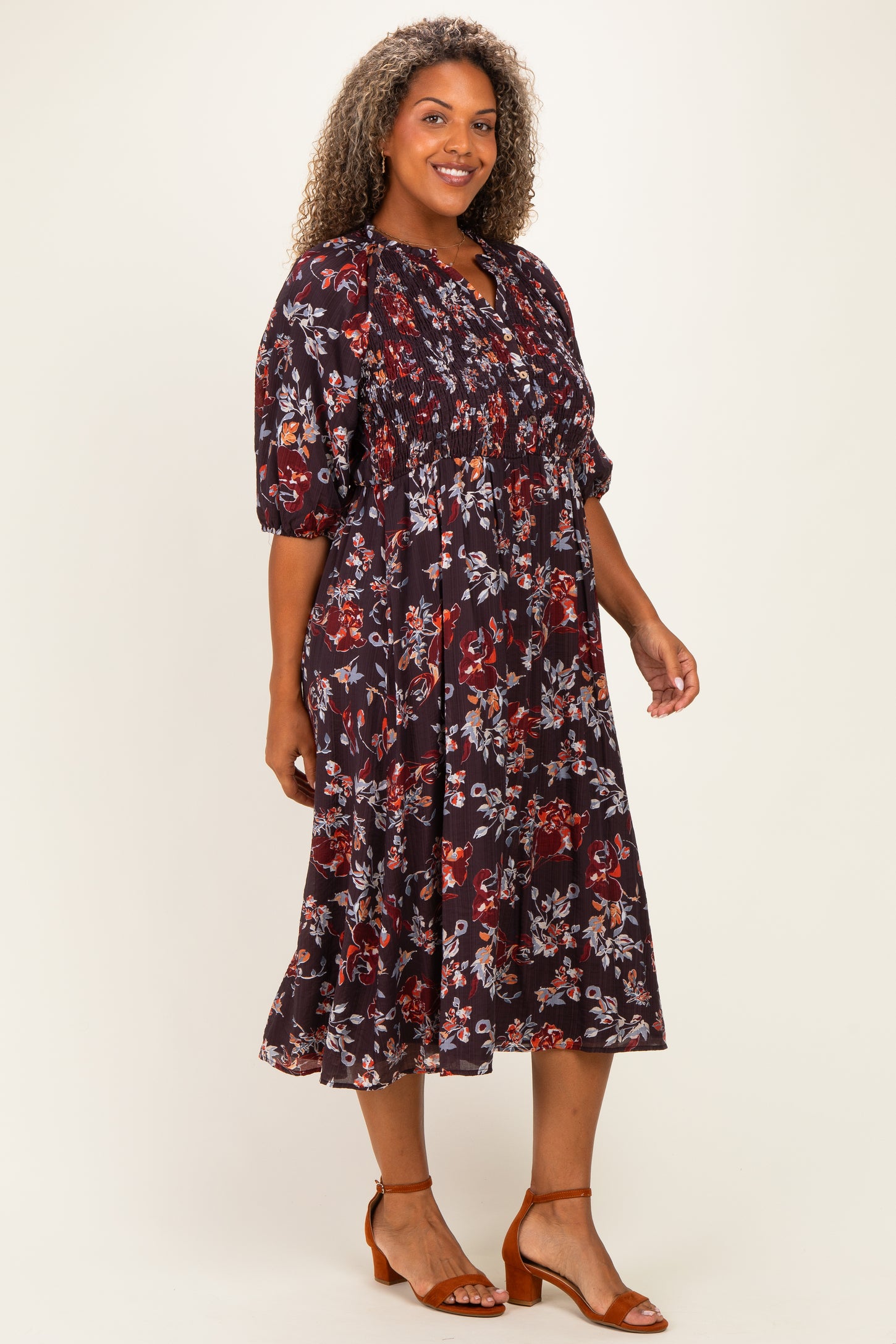 woman wearing a floral print plus-size midi dress with puff sleeves and a smocked bodice