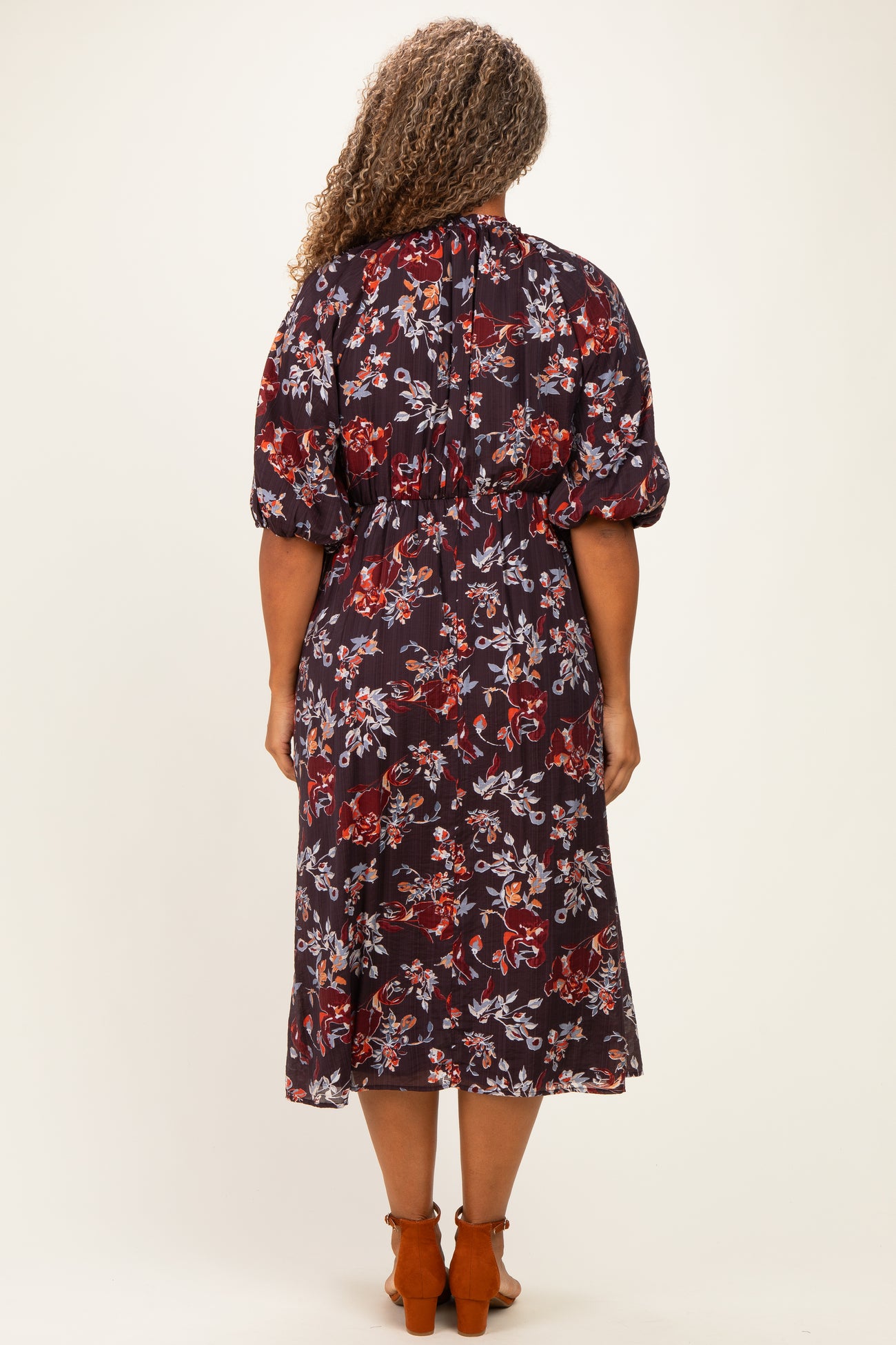 woman wearing a floral print plus size midi dress with puff sleeves and a cinched waist, shown from the back