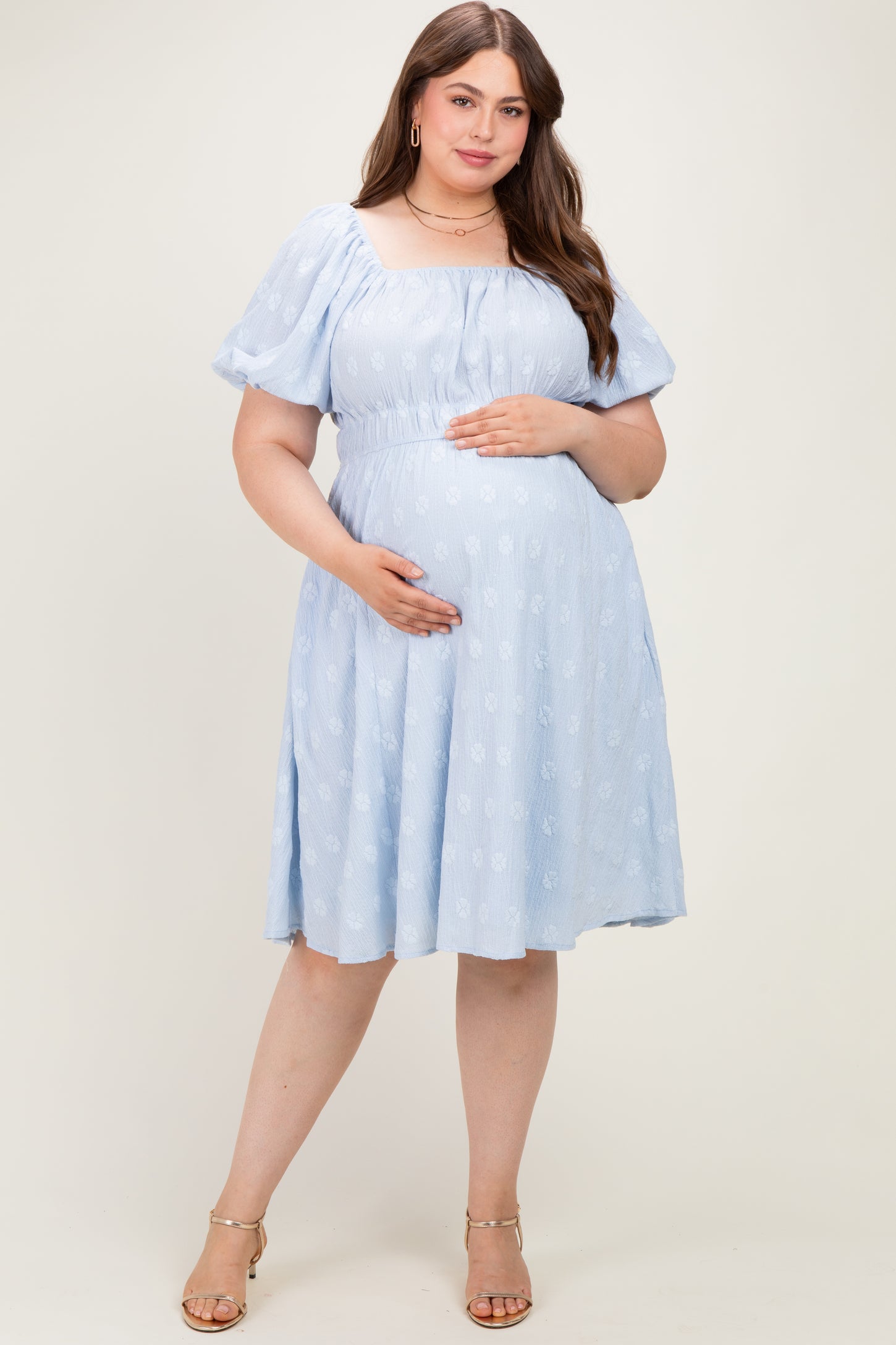 woman wearing a light blue off-the-shoulder maternity dress with puff sleeves and a visible baby bump