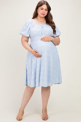woman wearing a light blue off-the-shoulder maternity dress with puff sleeves and a visible baby bump