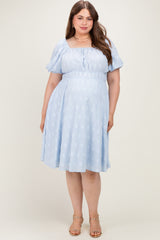 woman wearing a light blue maternity plus dress with puff sleeves and a cinched waist, showing a baby bump
