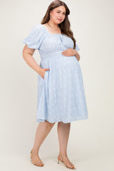 woman wearing a light blue floral maternity dress with short puff sleeves and pockets, holding her baby bump