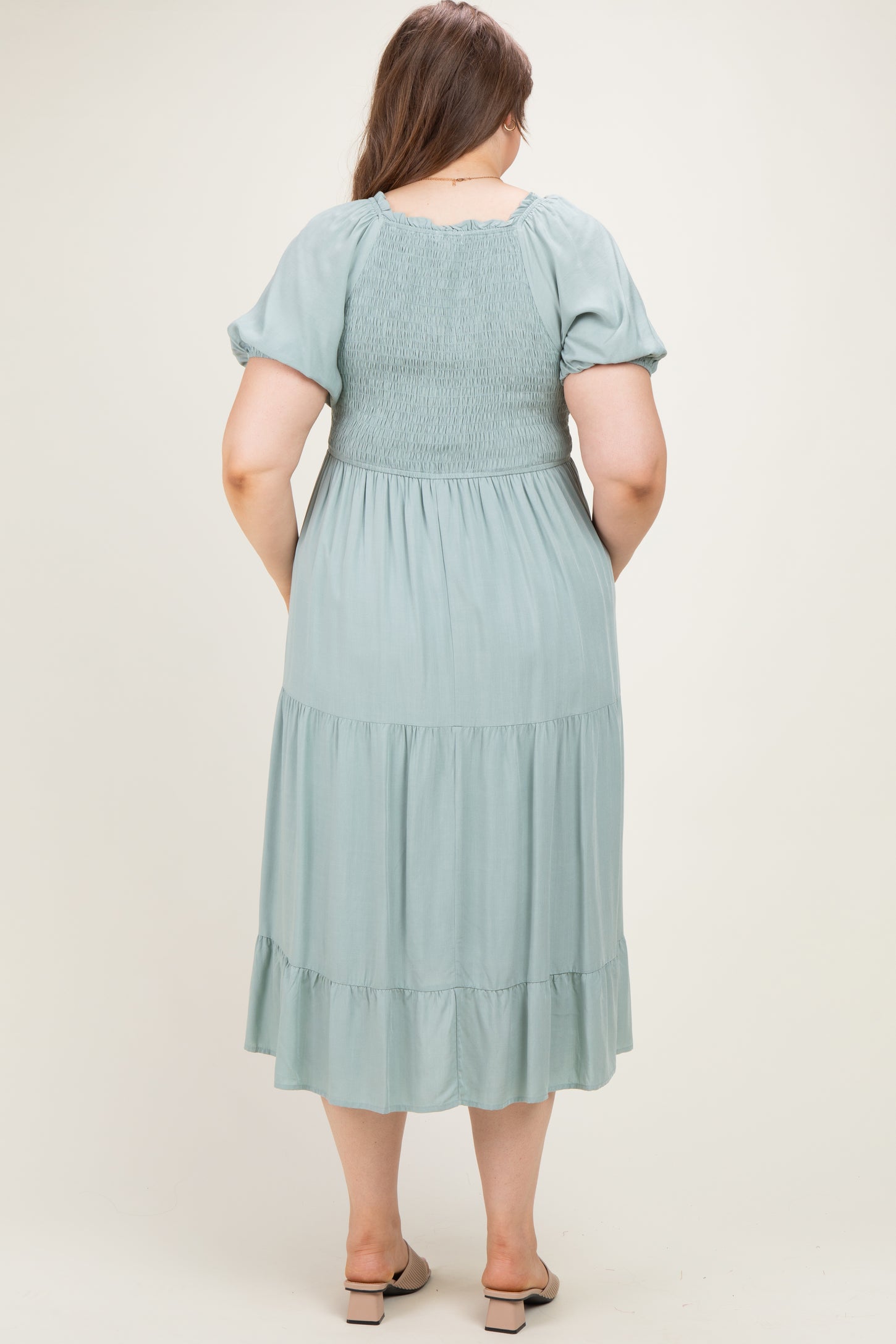 woman wearing a sage green maternity plus maxi dress with smocked bodice and tiered skirt, seen from the back