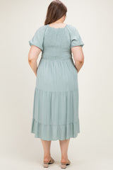 woman wearing a sage green maternity plus maxi dress with smocked bodice and tiered skirt, seen from the back