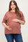 woman wearing a rust-colored maternity plus oversized t-shirt and holding her baby bump