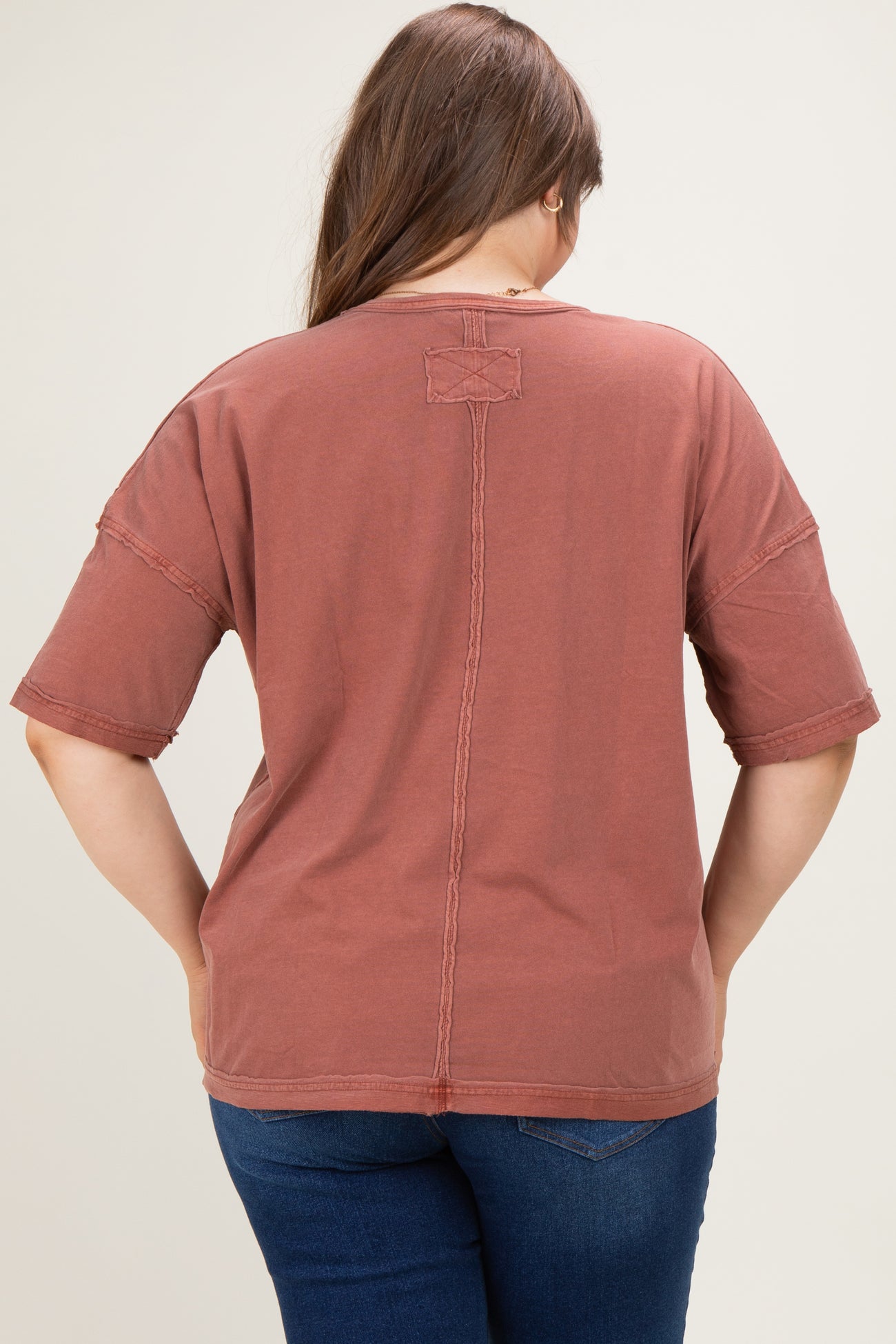 woman wearing a rust-colored maternity plus oversized t-shirt, viewed from the back, with casual style details