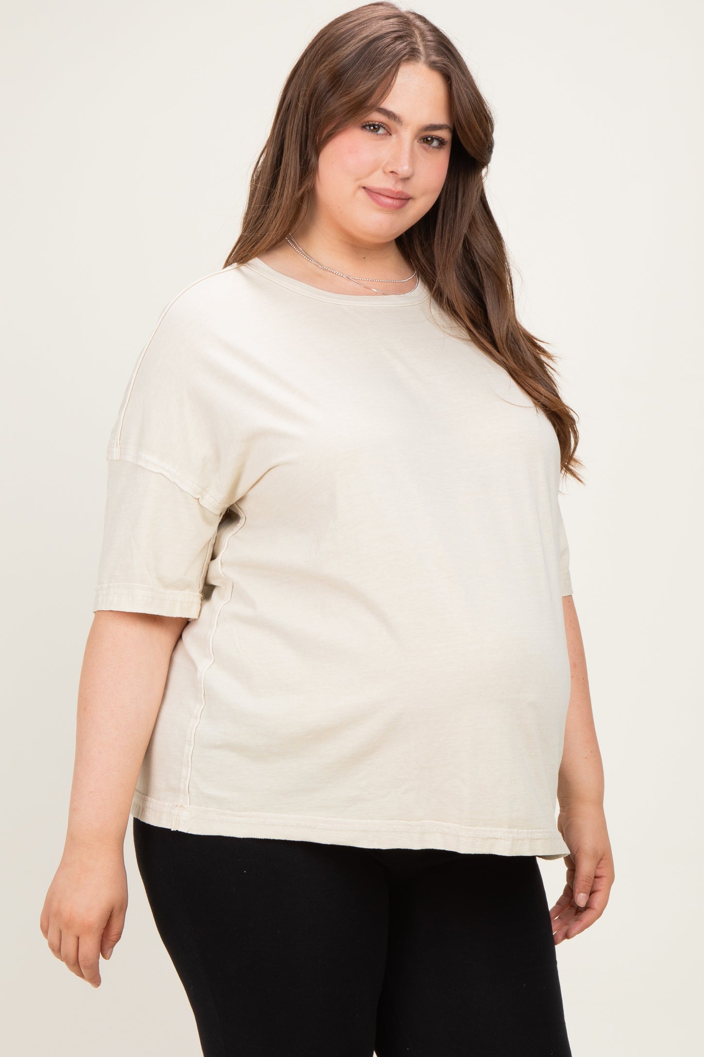 woman wearing a light beige oversized maternity t-shirt with short sleeves and a visible baby bump