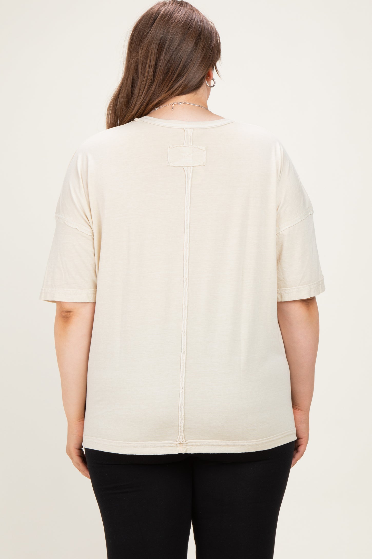 woman wearing a beige maternity plus t-shirt with a relaxed fit and decorative seam detail at the back