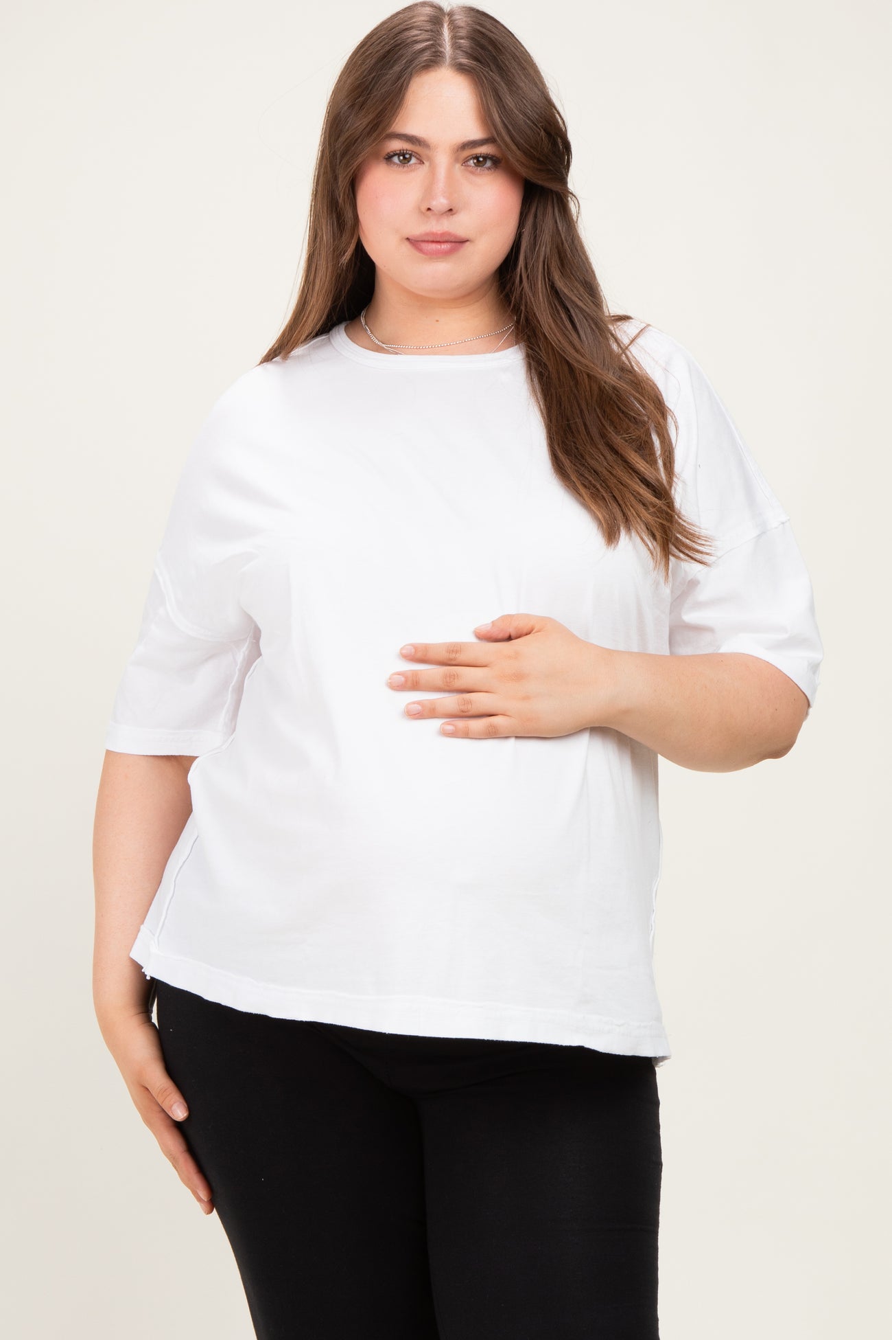 woman wearing a white short sleeve maternity top and holding her baby bump