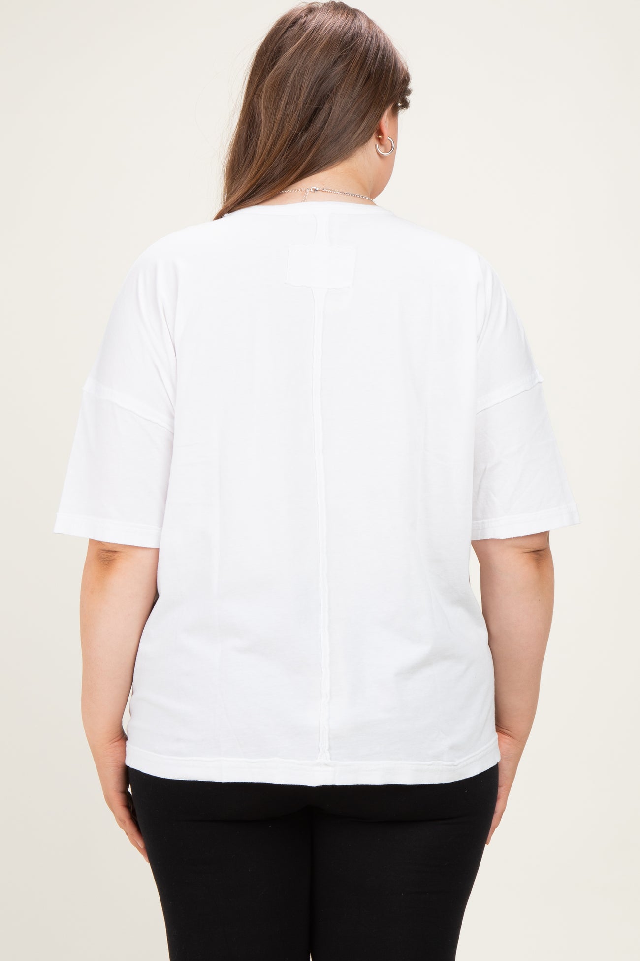 maternity plus woman wearing a white short sleeve back detail top with a relaxed fit and paired with black pants