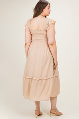 woman wearing a blush pink maternity plus dress with ruffled sleeves and a tiered hem, showcasing a relaxed fit