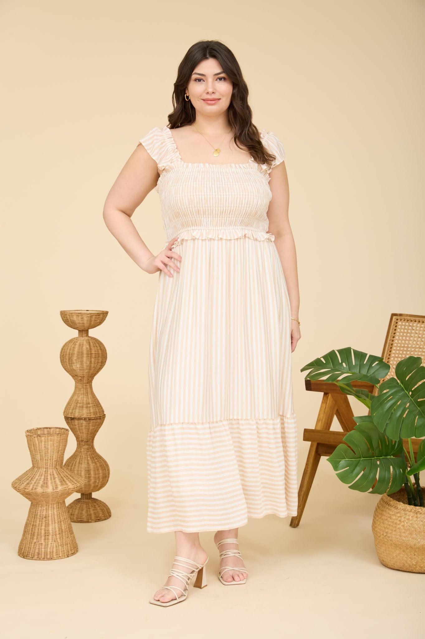 woman wearing a cream and beige striped plus size maxi dress with ruffled sleeves and a smocked bodice