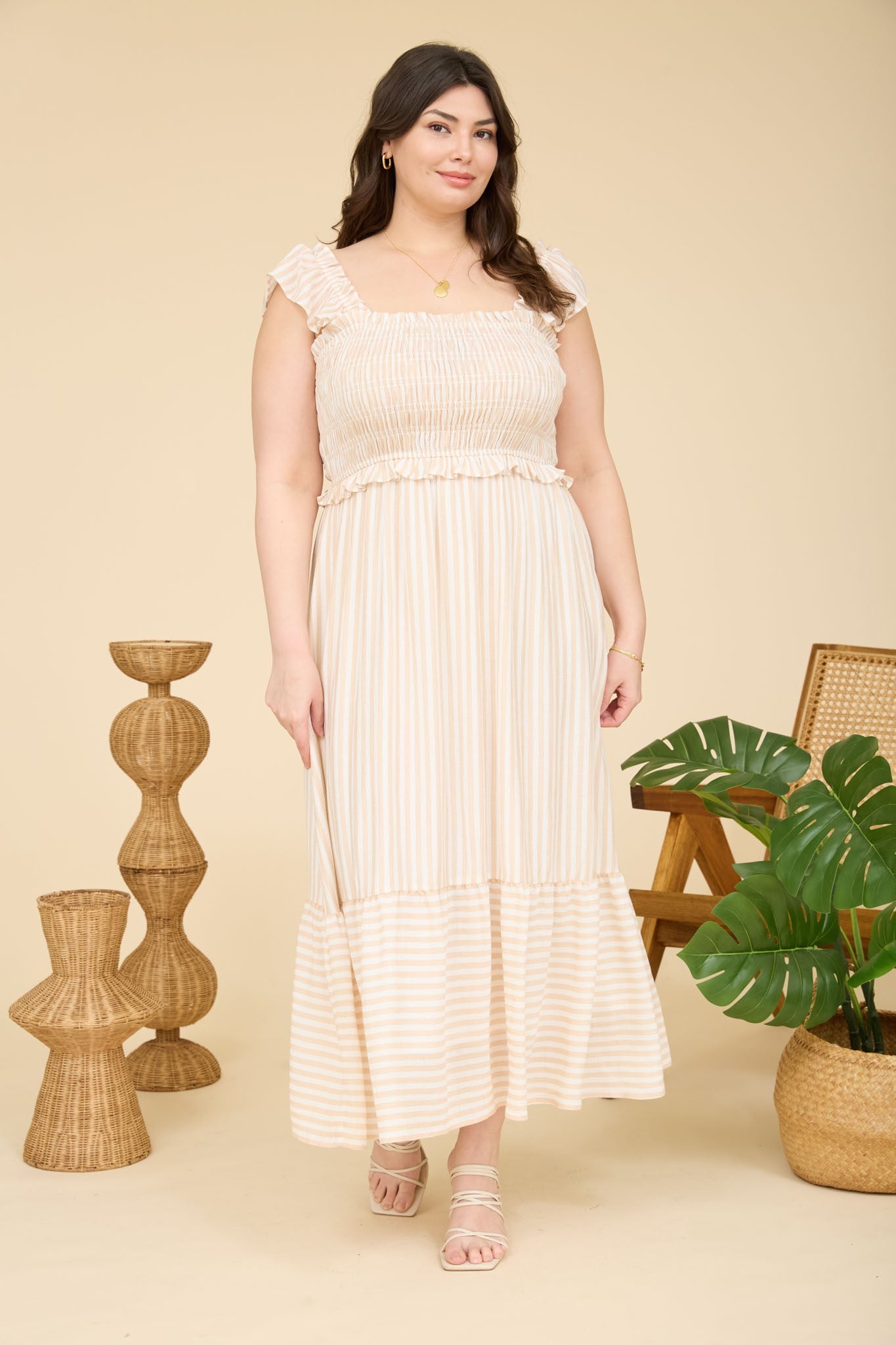 plus size woman wearing a light beige and cream striped maxi dress with ruffled sleeves and tiered hem
