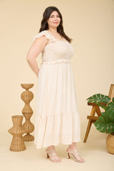 woman wearing a light beige and white striped plus size maxi dress with ruffle details and a tiered skirt