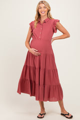woman wearing a rust-colored maternity dress with ruffle sleeves and a tiered skirt, gently cradling her baby bump