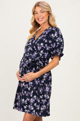 woman wearing a navy floral wrap maternity dress and showing her baby bump