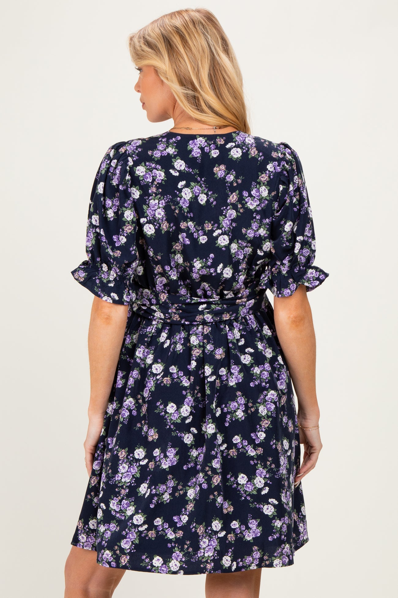 woman wearing a navy blue floral print maternity dress with short puff sleeves and a tie waist detail