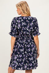 woman wearing a navy blue floral print maternity dress with short puff sleeves and a tie waist detail