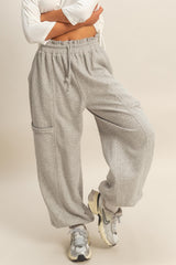 woman wearing gray relaxed fit sweatpants with a drawstring waist and side pocket, styled with sneakers