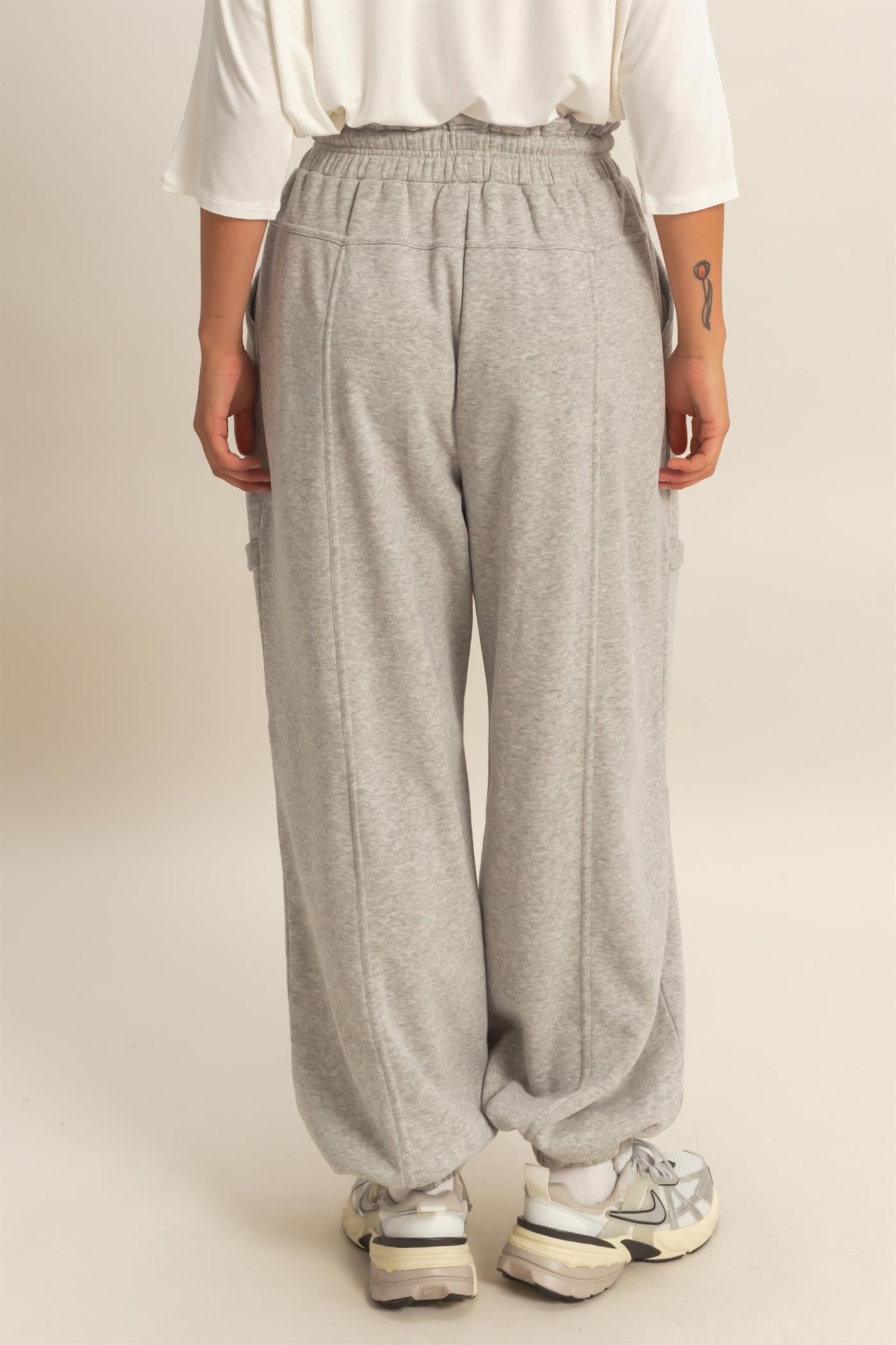woman wearing gray sweatpants with a relaxed fit and cargo pockets, shown from the back