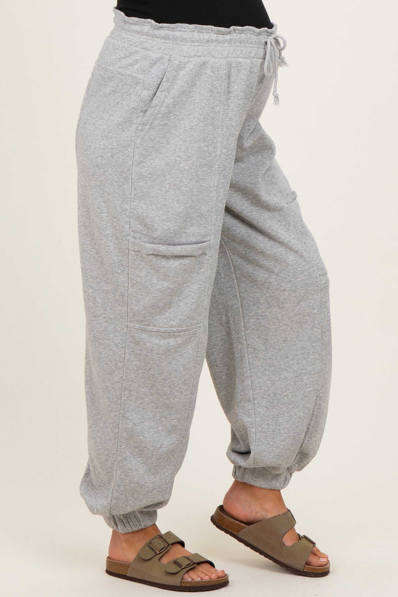 woman wearing gray maternity jogger pants with side pockets and cuffed ankles, styled with brown sandals