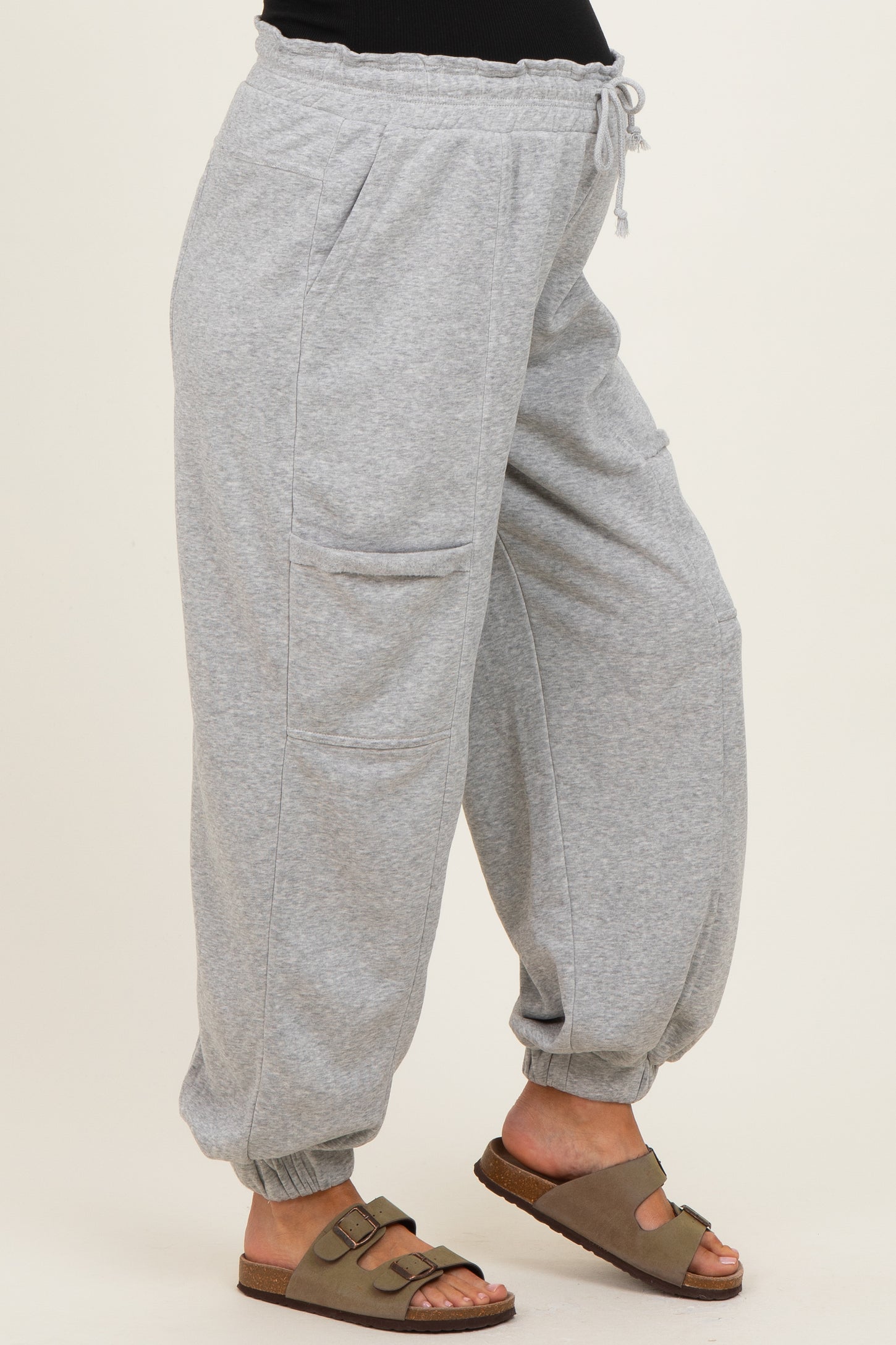 woman wearing gray maternity jogger pants with side pockets and cuffed ankles, styled with brown sandals