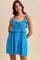 woman wearing a bright blue ruffled sundress with embroidered bodice and adjustable straps